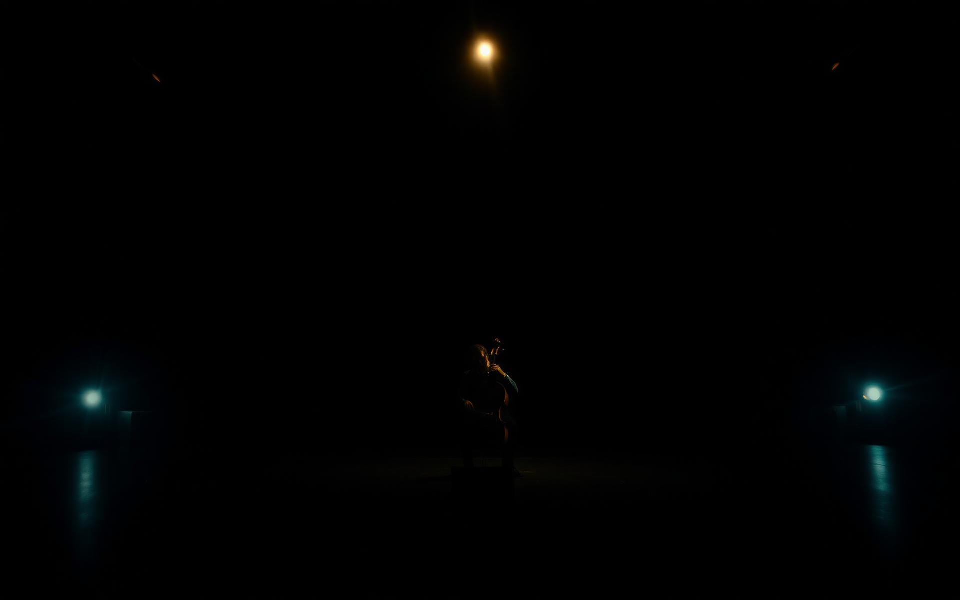 A cellist alone on a darkened concert stage